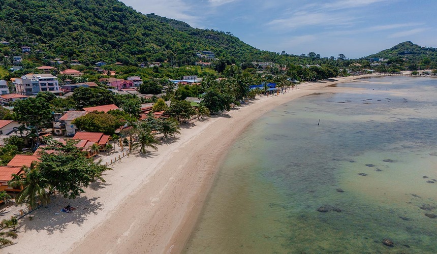 Peaceful stretch of golden sand and clear sea at Lamai Beach, perfect for relaxation.