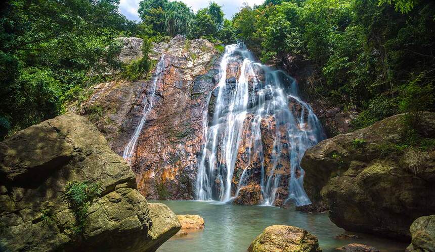Cascading waters surrounded by jungle at Na Muang Waterfalls, a top nature spot on Koh Samui.