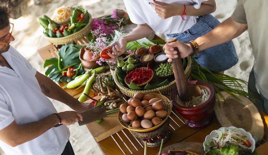 Tourist preparing traditional Thai dishes during a cooking class in Koh Samui.